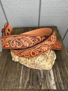 This is a hand tooled, lined leather belt made from veg tanned leather. There is a floral, leaf and scrollwork pattern throughout. This will fit a trophy buckle (secured by snaps) or a regular buckle, however neither are included in the listing. I hand dyed the leather and sewed the whole thing in contrasting cream thread. There is also a leather belt keeper in the snaps to help hold the belt tip in place (removable if not needed).  The belt measures 1.5 inches wide and 32 inches from the fold t Classic Hand Tooled Leather Belt Buckles, Western Style Engraved Leather Belt, Engraved Leather Western Belt, Custom Engraved Leather Belt Buckles, Traditional Hand Tooled Leather Belt Buckles, Traditional Leather Belt With Concho, Scrollwork Pattern, Tooled Leather Belts, Leather Tooling Patterns