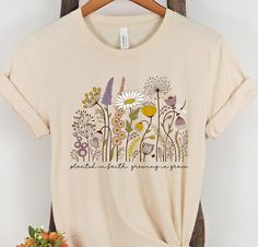 Quality: Our Women's Christian graphic t-shirts are professionally designed and printed with aesthetic love in the USA. We use the highest quality inks on Premium Bella + Canvas shirts for a look you can be proud of. You'll love the soft feel, comfort, and unique look of this Wildflower t-shirt. Imagine the compliments you'll receive. Perfect if you're looking for a Wildflower shirt, cottagecore clothing, Floral Shirt, Nature Shirt, or Christian clothing. Fit: Fits true to size for comfort that Wildflower Shirt Design, Pretty T Shirts, Plant T Shirt Designs, Cottagecore Graphic Design, T Shirt Phrases, T-shirt Designs, Flower Tshirt Design, Sweatshirt Painting, Wildflower Shirts