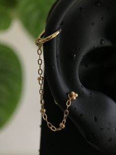 a close up of a black object with gold chains on it's end and a green plant in the background