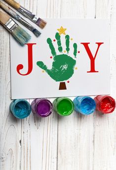 a handprinted sign with paint and brushes next to it on a white wooden surface