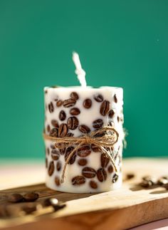 a candle with coffee beans on it sitting on top of a cutting board next to some seeds