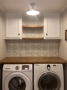 a washer and dryer in a small laundry room with white cupboards above