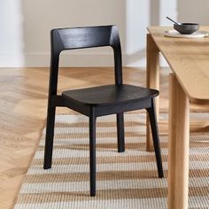 a black chair sitting on top of a wooden floor next to a dining room table