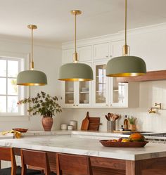 a kitchen with three pendant lights hanging over the island