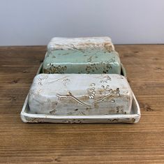 two rectangular ceramic containers sitting on top of a wooden table next to eachother