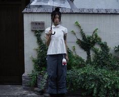 a woman standing in front of a building holding an umbrella