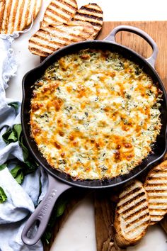 a skillet filled with cheese and crackers on top of a cutting board