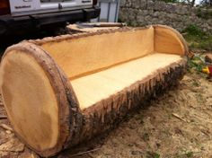 a large wooden bench sitting on top of a dirt field next to a white truck