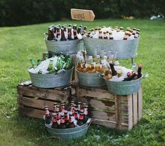 several buckets filled with beer sitting on top of a grass covered field next to trees