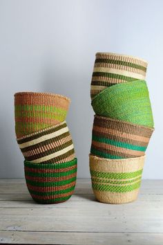 three woven baskets sitting on top of a wooden table next to each other in different colors