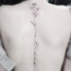 the back of a woman's neck with a flower tattoo on her left side