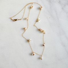 Dainty little puka shells and keshi white pearls dangle from a delicate 1.1mm 14k gold filled cable chain. Delicate Yellow Gold Charm Necklaces With Pearl Chain, Dainty Pearl Charm Necklace In 14k Gold, White 14k Gold Charm Necklace With Delicate Chain, Dainty 14k Gold Necklace With Pearl Charm, Dainty 14k Gold Filled Charm Necklace With Pearl Pendant, Delicate 14k Gold Filled Briolette Necklace, Delicate 14k Gold Filled Charm Necklaces With Pearl Pendant, Delicate 14k Gold-filled Dangle Charm Necklaces, Delicate 14k Gold-filled Charm Necklace With Pearl Pendant