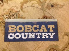 a sign that says bobcat country hanging on a carpeted area with floral designs