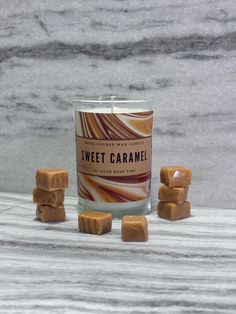 a small glass candle with caramel candy on the side next to some marshmallows