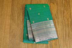 This stunning trendy kanchipuram saree is ready to wear for all occasions comes with a lovely peacock green color and peacock and coin butta all over the body. It comes with a silver zari border and a self attached blouse. Blouse is unstitched.  Wash Care: Dry Wash Note: Product color may slightly vary due to photographic lighting sources or your screen settings. Green Traditional Wear With Zari Weaving For Celebration, Green Handloom Traditional Wear For Celebration, Elegant Green Traditional Handloom Wear, Elegant Green Traditional Wear Handloom, Green Tussar Silk Saree For Celebration, Green Banarasi Silk Traditional Wear For Celebrations, Elegant Green Saree For Celebrations, Green Saree With Zari Weaving For Celebration, Green Raw Silk Saree For Celebration