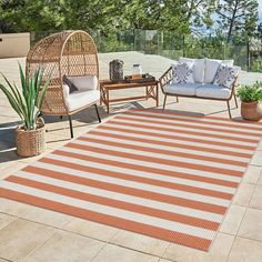 an outdoor area with two chairs and a rug on the ground next to some plants