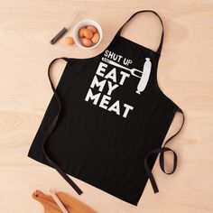 an apron with the words shut up eat my meat on it next to eggs and utensils