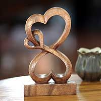 two small vases sitting next to each other on a table with a wooden sculpture in the shape of a heart