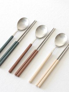 five spoons with different colored handles are lined up in a row on a white surface