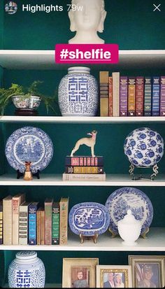 there are many blue and white vases on the shelves in this bookcase with books