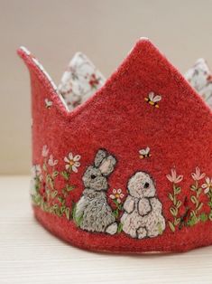 a red felt crown with two rabbits on it