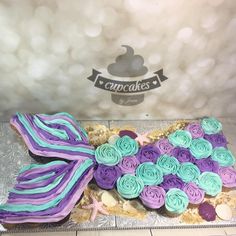 there is a cake that looks like a mermaid tail with flowers on it and purple icing