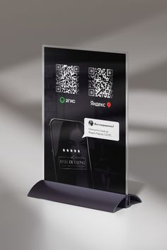 a black and white display with qr code on the front, next to an iphone