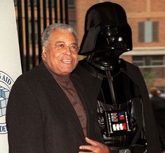 a man standing next to a darth vader statue