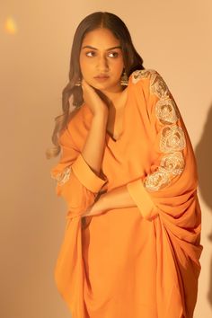 Rust orange pure chiffon draped top with resham, sequins and cutdana embroidered sleeves. Comes with straight pant.
Components: 2
Pattern: Embroidered
Type Of Work: Resham, Sequins, Cutdana
Neckline: V Neck
Sleeve Type: Draped Sleeves
Fabric: Pure chiffon
Color: Orange
Other Details: 
Attached lining
Occasion: Work - Aza Fashions Draped Sleeves, Embroidered Sleeves, Pure Chiffon, Drape Sleeves, Draped Top, Top And Pants Set, Rust Orange, Fashion App, Pant Set