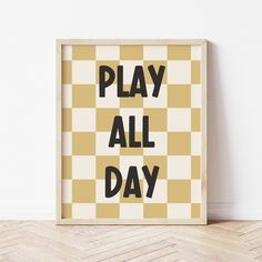 a wooden frame with the words play all day printed in black and yellow on it