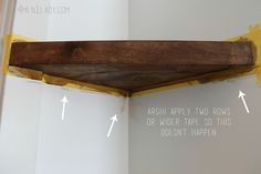 the corner of a shelf is being painted white and has yellow tape on it, along with an arrow pointing to the right