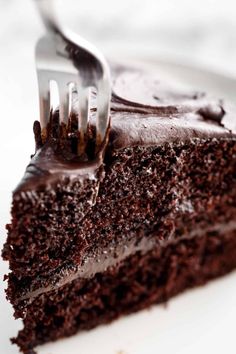 a piece of chocolate cake on a plate with a fork sticking out of the slice