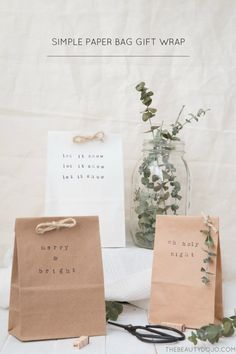 some brown paper bags sitting on top of a table next to a vase filled with flowers