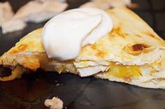 a quesadilla with sour cream on top is sitting on a countertop