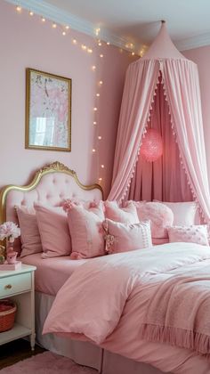 a bed with pink sheets and pillows in a room that has lights on the walls