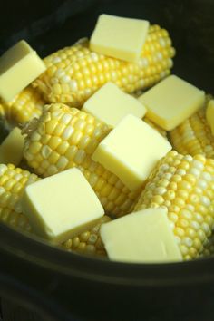 corn with butter and cubed cheese in a crock pot on the stove top