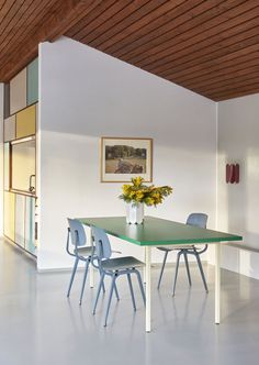 a green table with blue chairs in a white room