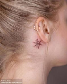 a woman's ear with a small snowflake tattoo on her left side