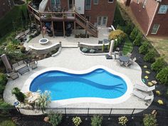 an aerial view of a backyard with a swimming pool and deck area, surrounded by landscaping