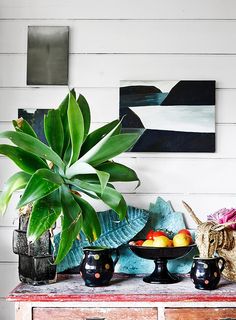 a table topped with vases filled with fruit next to a painting on the wall