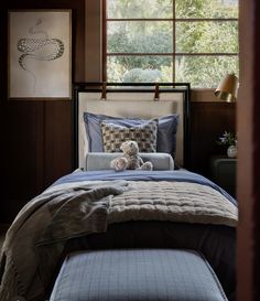 a teddy bear sitting on top of a bed in a room with wood paneling