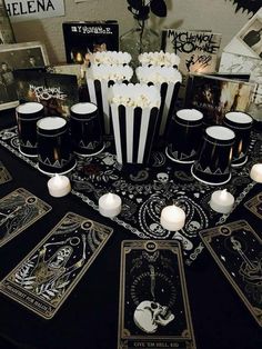 a table topped with cards and candles on top of a black cloth covered tablecloth