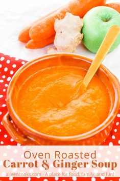 carrot and ginger soup in an orange bowl on a red polka dot tablecloth with fresh vegetables