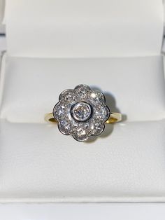 18ct Yellow Gold & Diamond Flower Cluster Ring - 1.00CT  This is a gorgeous ring, A classically designed Diamond Daisy Cluster Ring with nine Brilliant Cut Diamonds set extremely close together to give a fabulous overall appearance when worn. All the Diamonds are very bright and clean and are rim set. The total diamond weight is an impressive 1.00 carat. The ring has very attractive under gallery work which allows lots of light through and the diamonds to sparkle immensely. This ring is set in t Yellow Gold Flower-shaped Diamond Ring, Yellow Gold Flower Diamond Ring With Prong Setting, Classic 14k Gold Round Flower Ring, Classic Jewelry With Brilliant Cut In Flower Shape, Classic Round Flower Ring In 14k Gold, Classic White Gold Flower Ring With Rose Cut Diamonds, White Gold Brilliant Cut Ring In Flower Shape, White Gold Flower Shape Ring With Brilliant Cut, Classic Flower-shaped Jewelry With Brilliant Cut