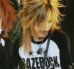 two young women with long hair and piercings on their ears, one holding a guitar