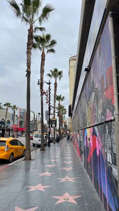 the hollywood walk of fame is decorated with pink stars and palm trees on a cloudy day