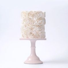 a three tiered cake with white frosting roses on it's top and bottom