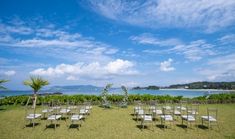 rows of chairs set up in the grass for an outdoor wedding ceremony overlooking the ocean