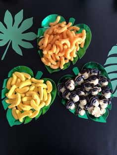 three plates filled with different types of food on top of a black table next to leaves