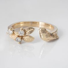 two gold rings with flowers and leaves on white background, one has a diamond in the middle